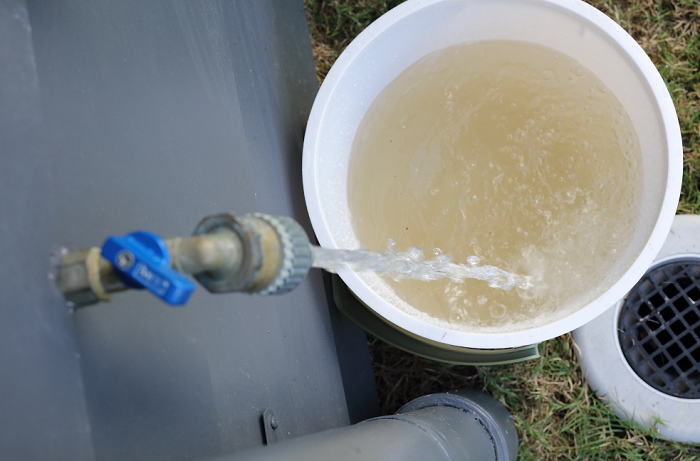 Moderately dirty water running from tap into bucket to clear pipes