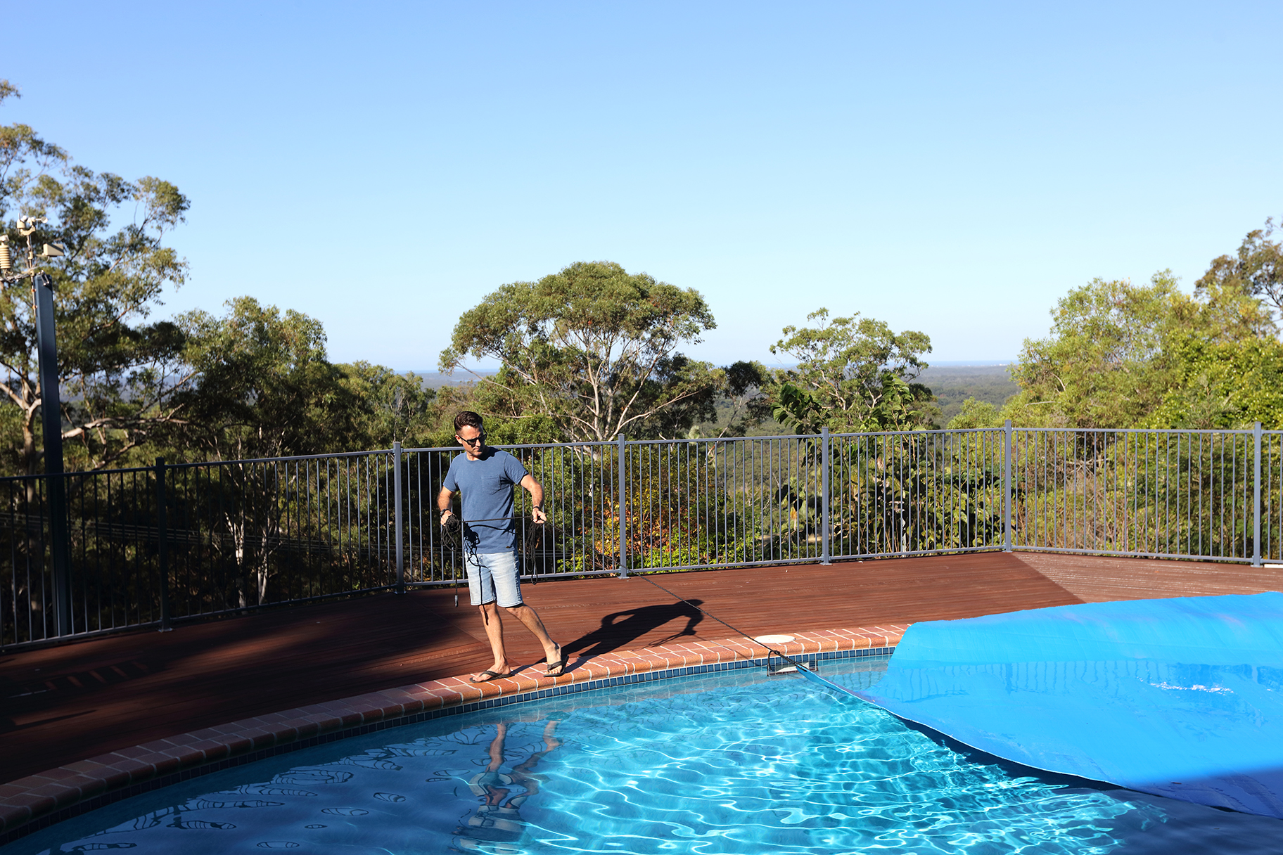 Man covering residential pool with blue tarp