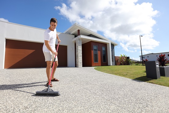 Man sweep driveway with broom